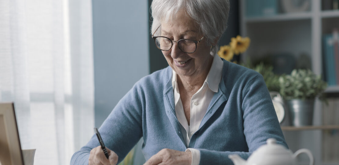 Senior woman writing on a notebook